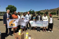 Robert and Paul with Sunrise Africa Relief banner stand beside Africans holding Women's Federation for World Peace banner