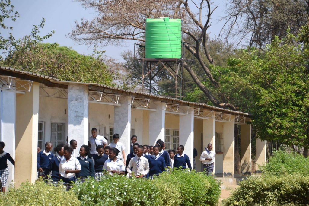 Large group of school children group outside the school, with new water tower in background